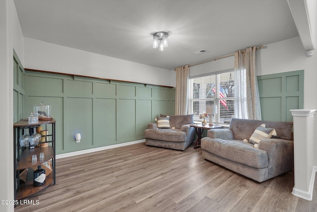 sitting room featuring a decorative wall, visible vents, and light wood-type flooring