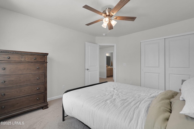 bedroom with a closet, baseboards, light colored carpet, and a ceiling fan