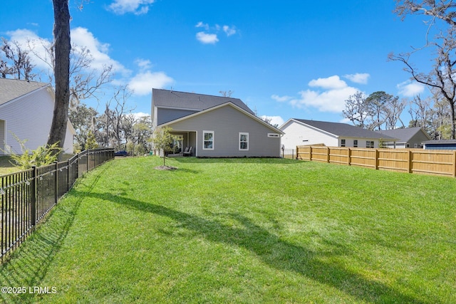 rear view of house featuring a lawn and a fenced backyard