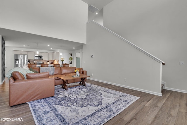 living room featuring stairway, recessed lighting, baseboards, and wood finished floors