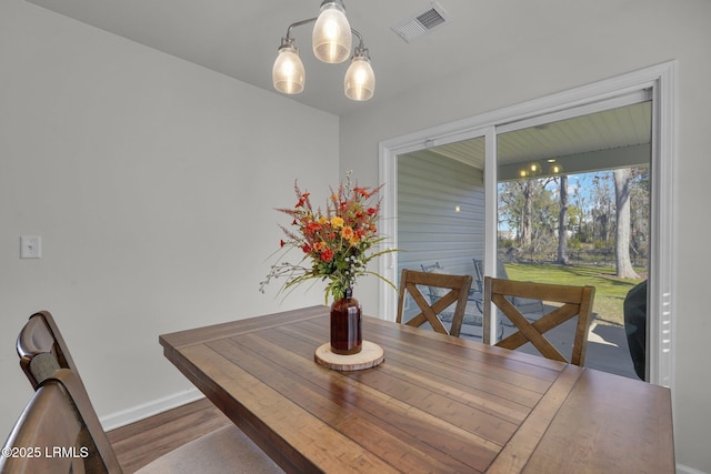 dining room featuring wood finished floors, baseboards, and visible vents