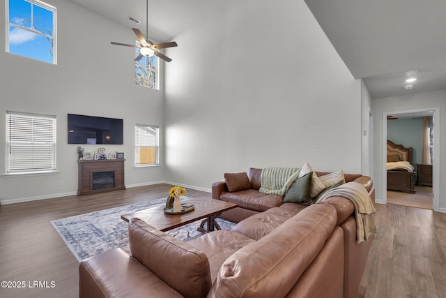 living room with visible vents, wood finished floors, a fireplace, baseboards, and ceiling fan