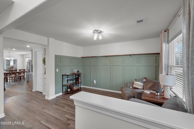 interior space with a notable chandelier, visible vents, a decorative wall, and wood finished floors