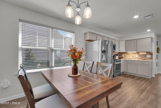 dining room with baseboards, visible vents, light wood-style flooring, recessed lighting, and a notable chandelier