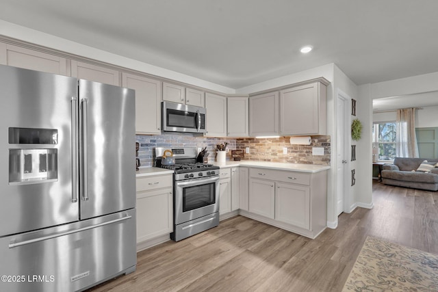 kitchen with light wood-style flooring, gray cabinetry, decorative backsplash, light countertops, and stainless steel appliances