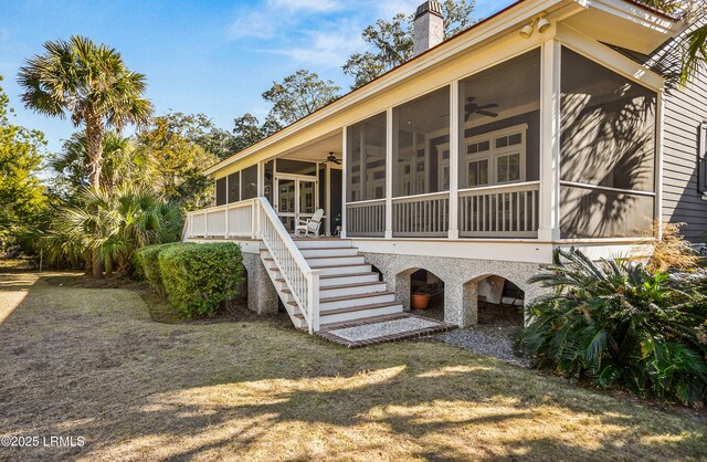 view of side of home with a lawn, a sunroom, and ceiling fan