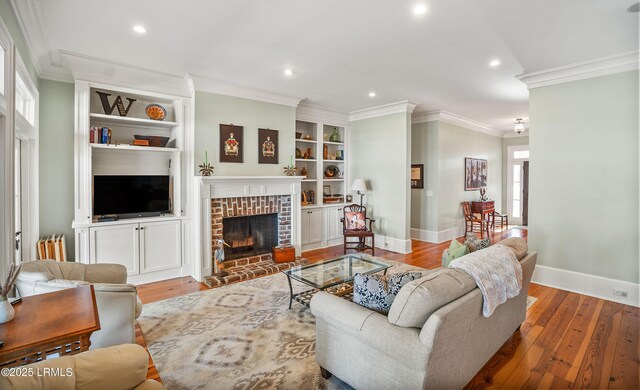 living room with a healthy amount of sunlight, light hardwood / wood-style flooring, a fireplace, and built in shelves