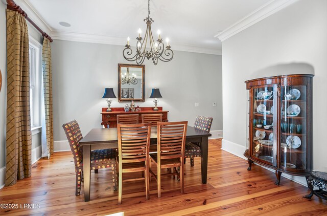 dining space with an inviting chandelier, light hardwood / wood-style flooring, and ornamental molding