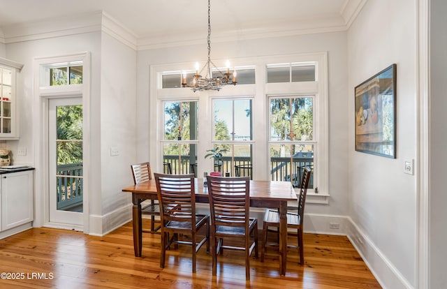 dining space featuring crown molding, a notable chandelier, and light wood-type flooring