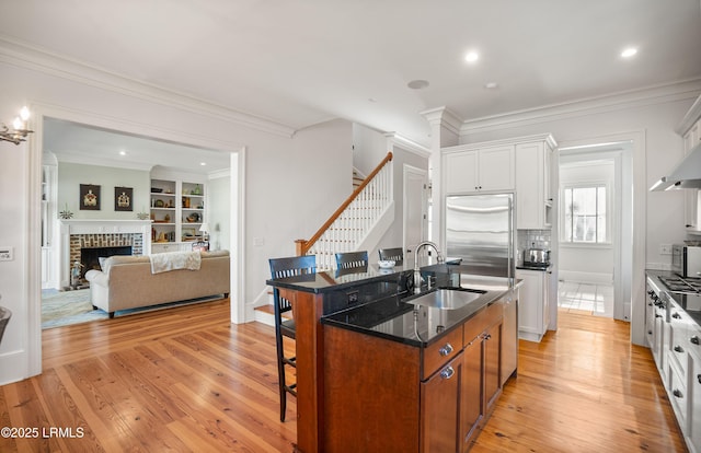 kitchen featuring stainless steel appliances, white cabinetry, a kitchen island with sink, and a kitchen breakfast bar