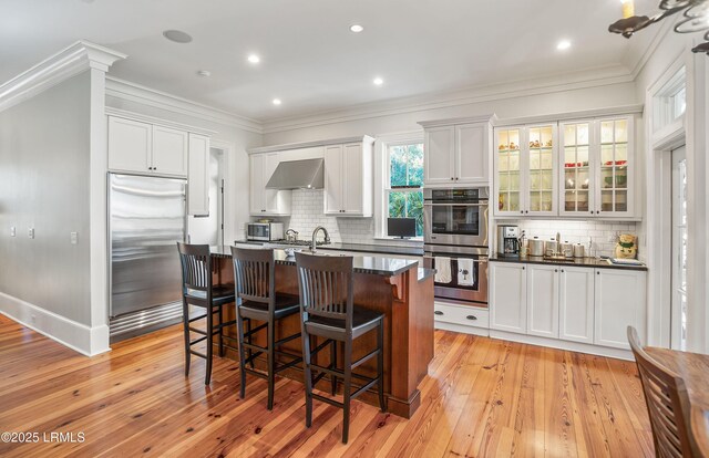 kitchen featuring white cabinetry, stainless steel appliances, tasteful backsplash, extractor fan, and a kitchen island