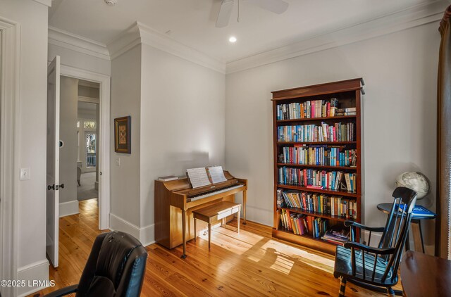 sitting room with wood-type flooring, ornamental molding, and ceiling fan