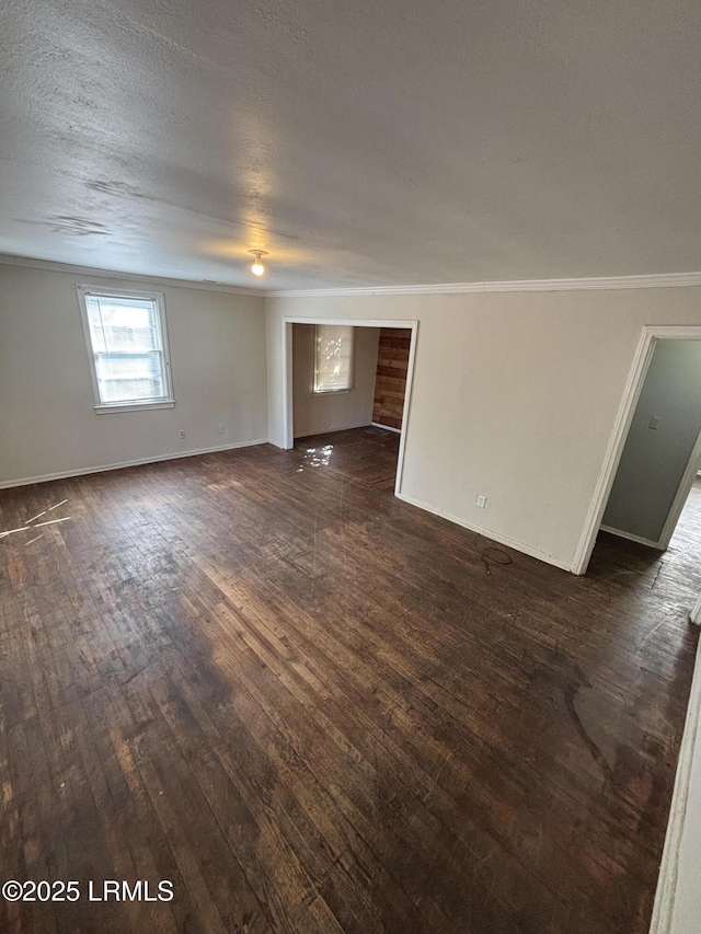 unfurnished living room with baseboards, a textured ceiling, ornamental molding, and dark wood-style flooring