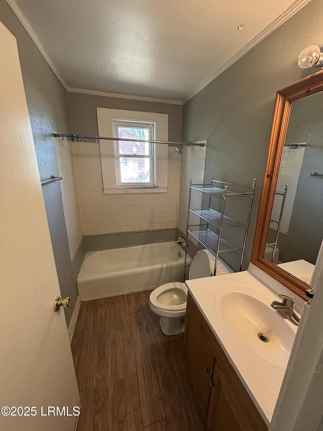 bathroom featuring toilet, ornamental molding, wood finished floors, bathtub / shower combination, and vanity