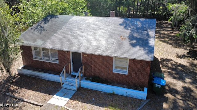 view of front of property featuring entry steps, a chimney, and brick siding