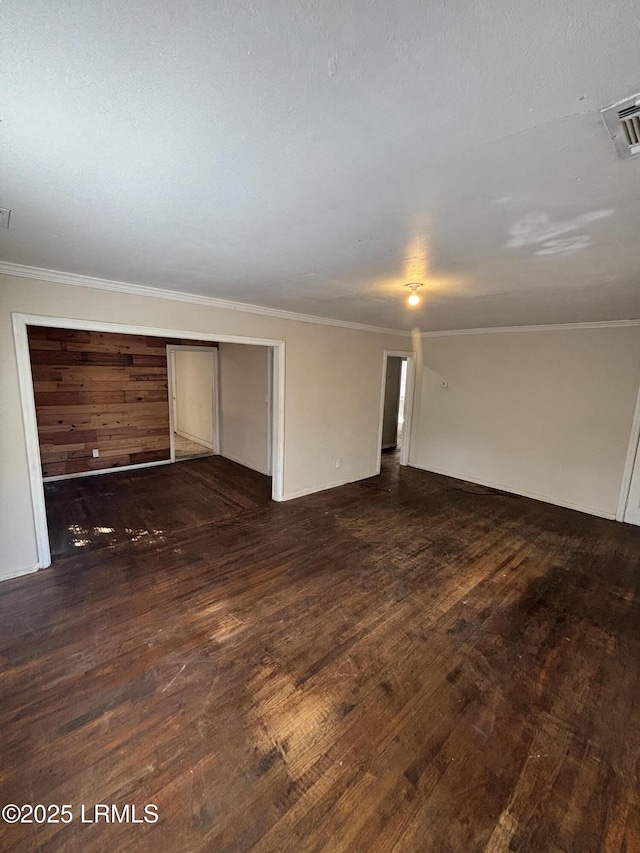 empty room with ornamental molding, dark wood finished floors, and visible vents