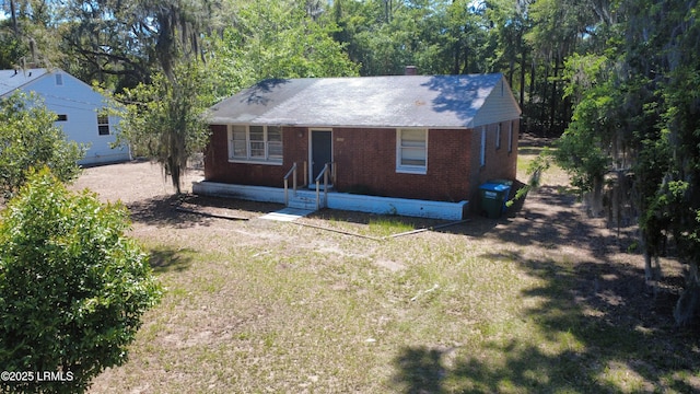 view of front of home featuring a chimney, a front yard, and brick siding