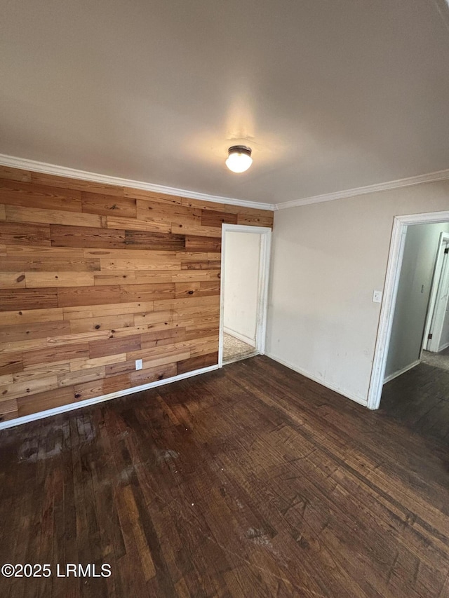 unfurnished room featuring crown molding, wooden walls, and hardwood / wood-style flooring