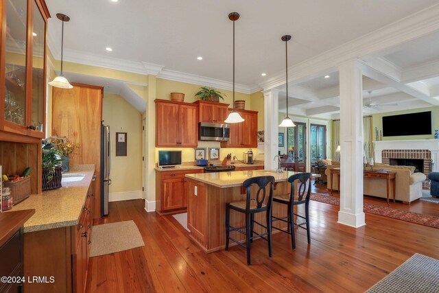 kitchen featuring appliances with stainless steel finishes, light stone countertops, decorative columns, and hanging light fixtures