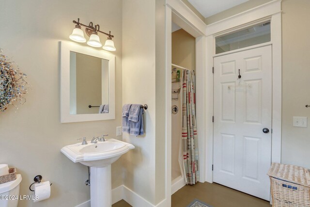 bathroom featuring toilet and curtained shower