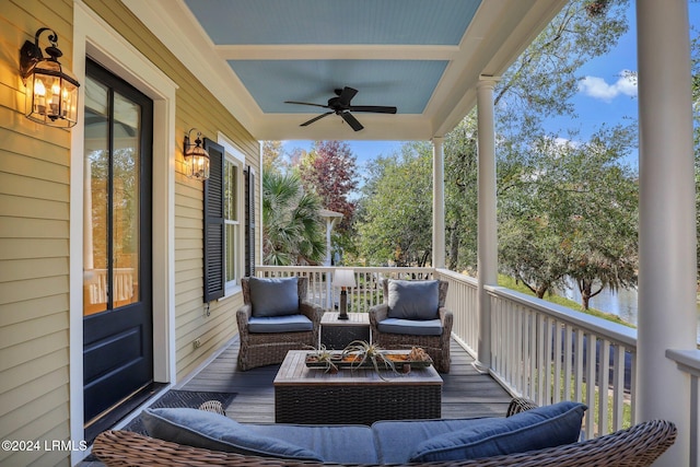 wooden deck with a water view, ceiling fan, and an outdoor living space