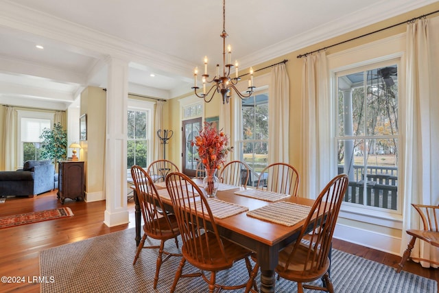 dining space featuring crown molding, an inviting chandelier, dark hardwood / wood-style flooring, and decorative columns