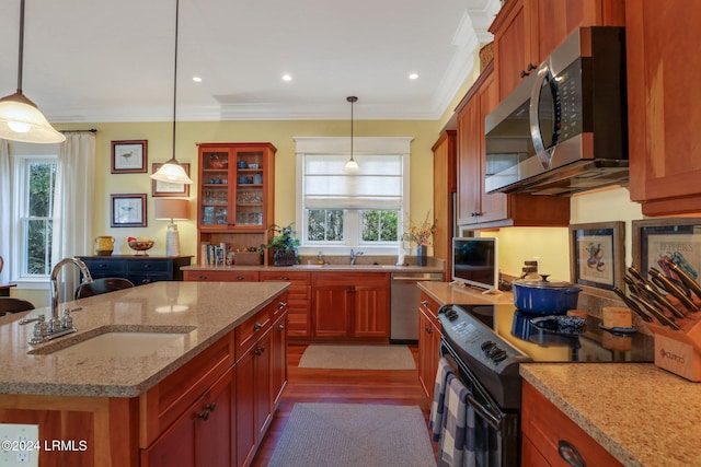 kitchen featuring sink, crown molding, light stone counters, appliances with stainless steel finishes, and a kitchen island