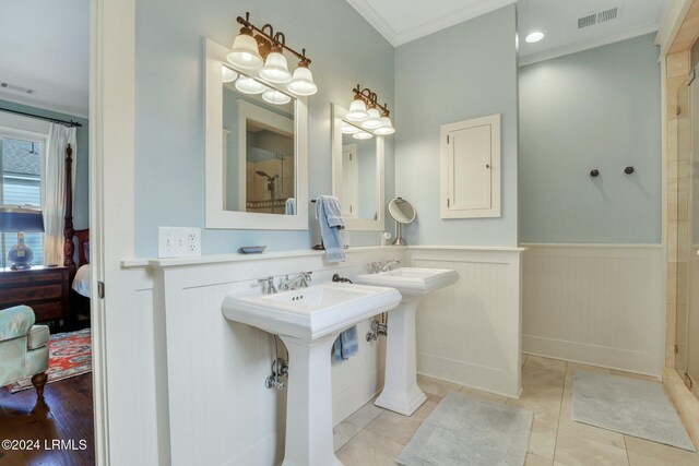 bathroom featuring dual sinks, ornamental molding, tile patterned floors, and a shower