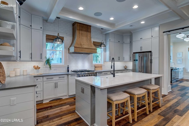 kitchen with dark hardwood / wood-style floors, a kitchen bar, a kitchen island with sink, stainless steel appliances, and custom range hood