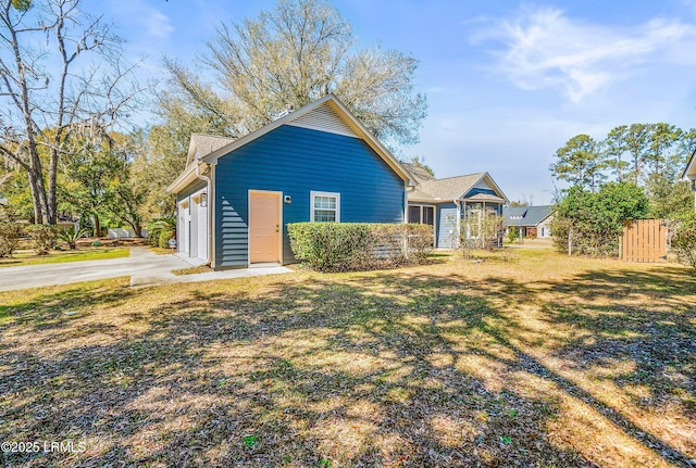 view of front facade featuring a front lawn, an attached garage, fence, and driveway