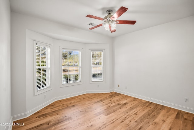 unfurnished room featuring a ceiling fan, visible vents, light wood-style floors, and baseboards