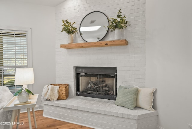 details with visible vents, a fireplace, baseboards, and wood finished floors