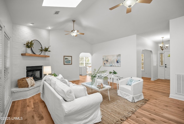 living room featuring visible vents, a fireplace, arched walkways, and light wood-type flooring