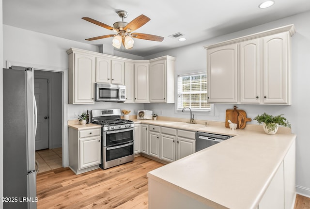 kitchen featuring visible vents, a sink, recessed lighting, stainless steel appliances, and a peninsula