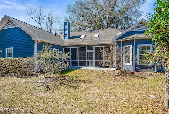 rear view of house with a yard, a chimney, and a sunroom