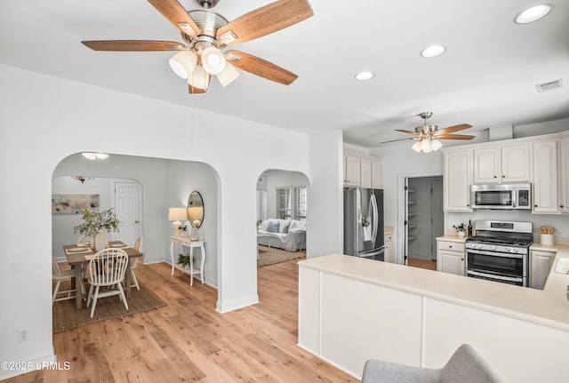 kitchen with light wood finished floors, arched walkways, visible vents, and appliances with stainless steel finishes