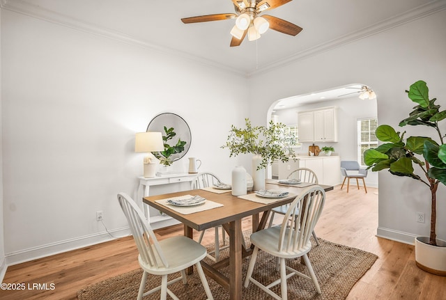 dining area featuring light wood finished floors, baseboards, and ornamental molding