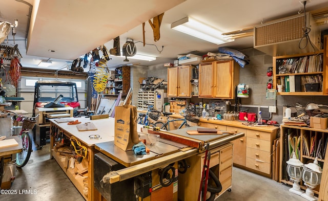 kitchen with light brown cabinetry, concrete floors, and concrete block wall