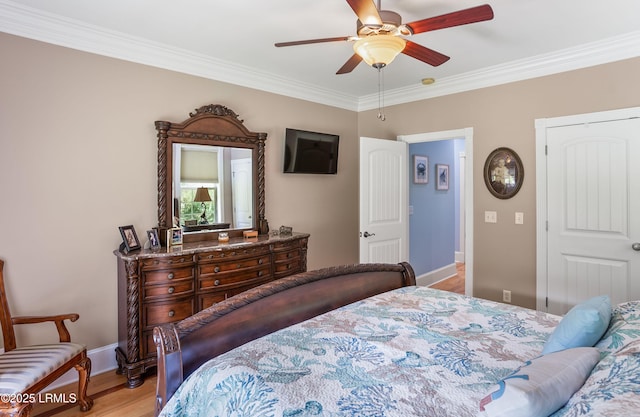 bedroom with baseboards, ornamental molding, wood finished floors, a closet, and a ceiling fan