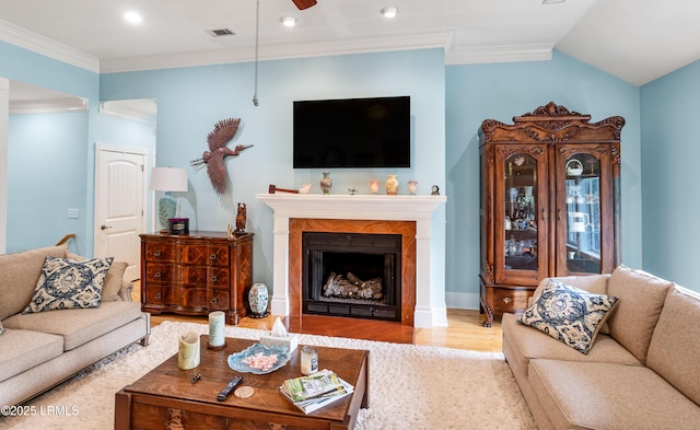 living area featuring ornamental molding, a fireplace, a ceiling fan, and wood finished floors