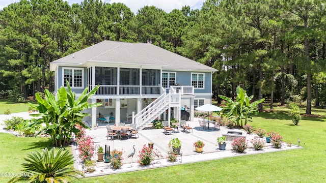 back of property with a yard, a sunroom, outdoor dining space, and a patio area