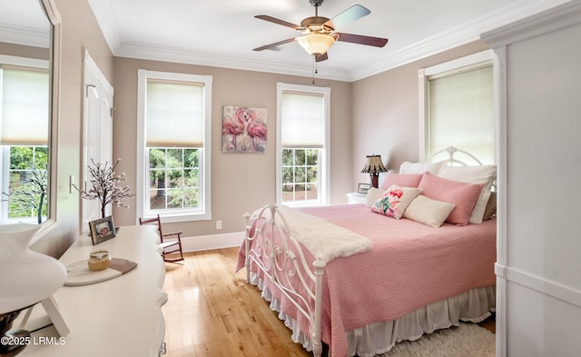 bedroom featuring light wood-style flooring, baseboards, ornamental molding, and multiple windows