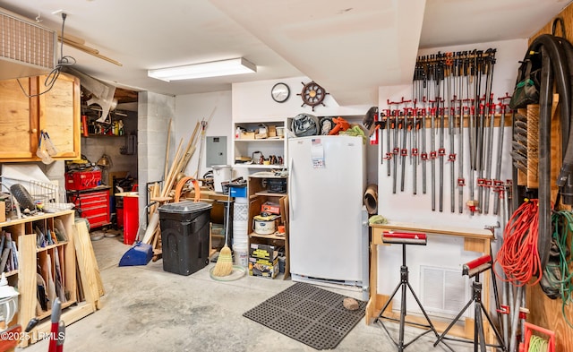 interior space with electric panel, visible vents, a workshop area, and concrete flooring