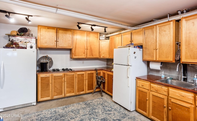 kitchen with dark countertops, concrete floors, freestanding refrigerator, and a sink