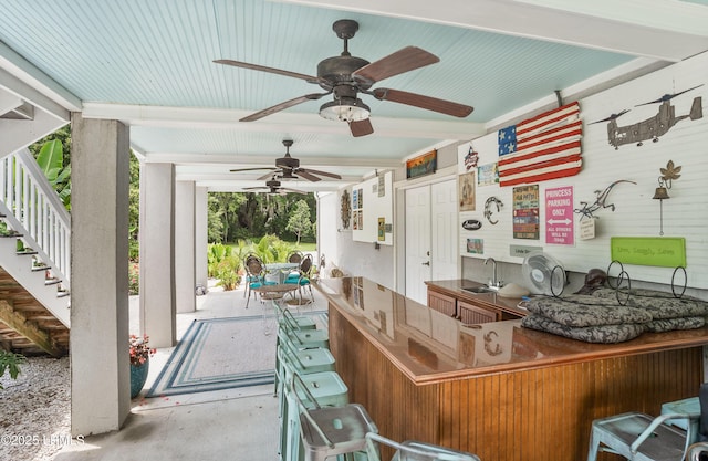 view of patio / terrace with outdoor dining space, stairs, a ceiling fan, and a sink