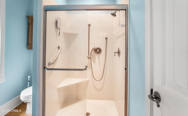 bathroom featuring baseboards, toilet, and a shower stall