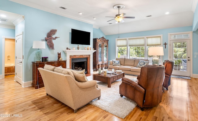 living area with visible vents, baseboards, ornamental molding, light wood-style flooring, and a fireplace