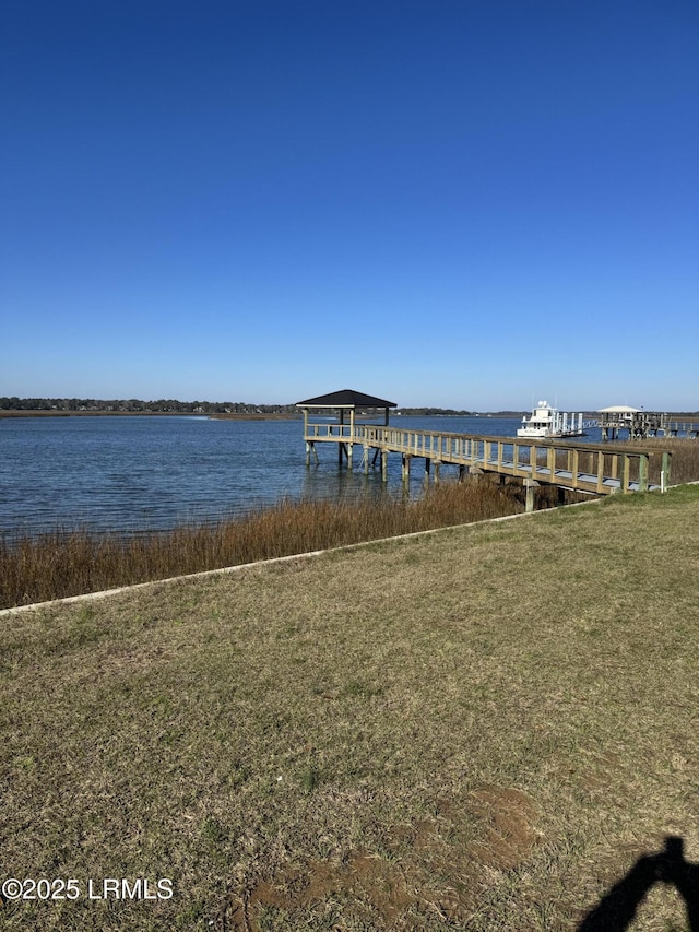 dock area with a water view and a lawn