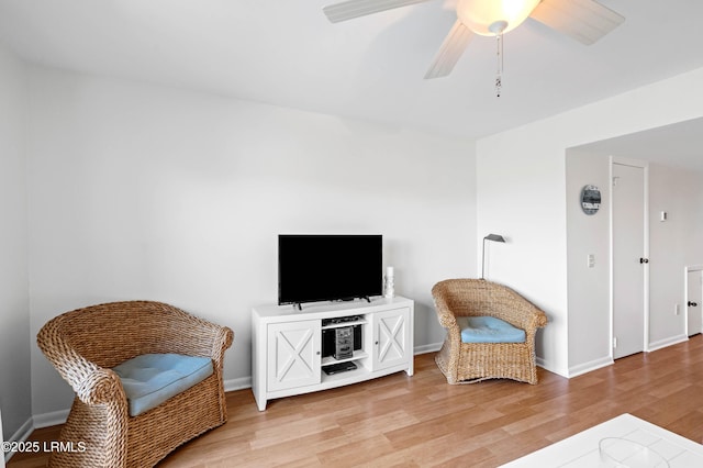 living area with light wood-type flooring, ceiling fan, and baseboards