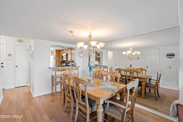 dining space with a chandelier, light wood finished floors, and baseboards